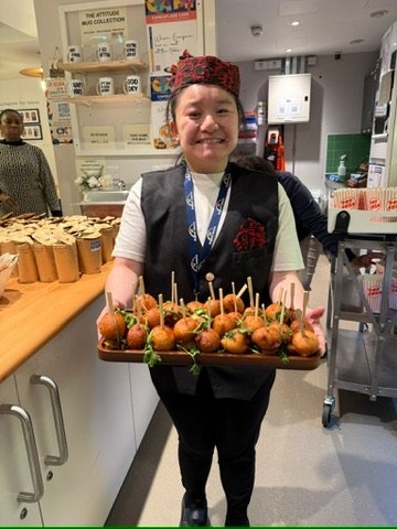 Student in silver service attire holding a canapé tray
